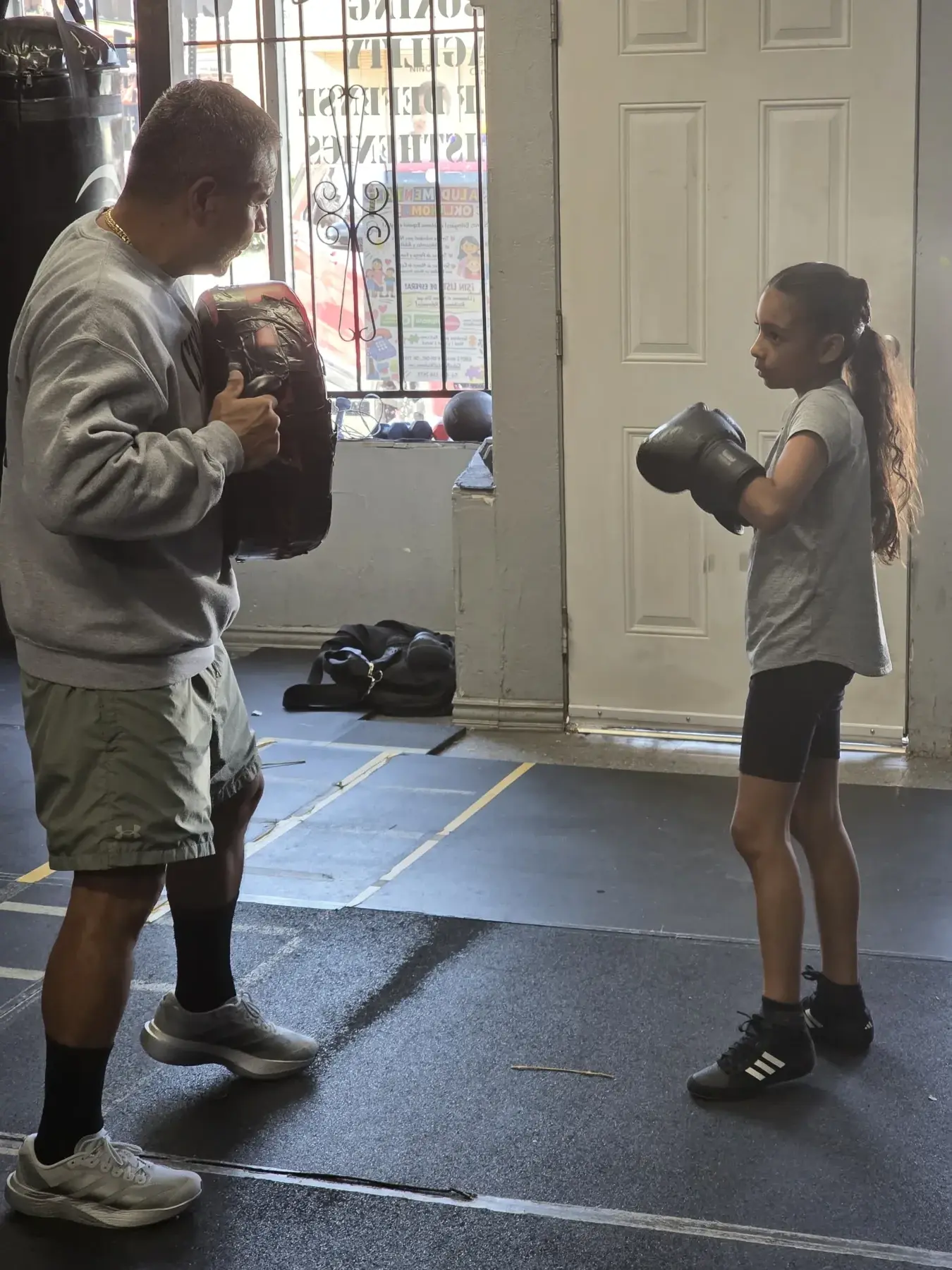 A Celda 151 coach works one-on-one with a young boxer during pad training